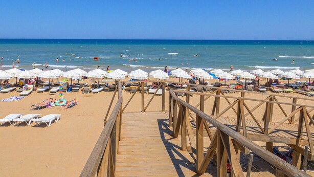 A wooden boardwalk leading to a beach with white umbrellas and sun loungers. - 2 bedroom gorgeous apartment in Torrevieja (Torrevieja)