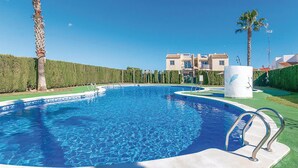 A swimming pool with a clear blue water, surrounded by a well-maintained lawn and palm trees. - 2 bedroom gorgeous apartment in Torrevieja (Torrevieja)