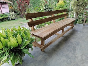 A wooden bench in a garden with various plants. - Peace and Tranquility (Lehigh Acres)