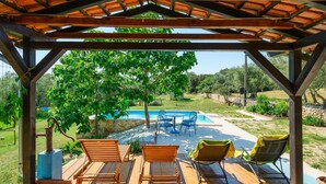 Un espace extérieur abrité comprenant une piscine, des bancs en bois et des chaises longues.