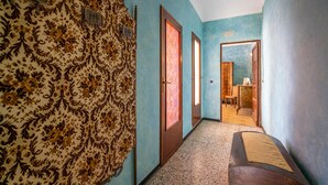 A hallway with patterned wallpaper, wooden doors, and a bench. - Beautiful apartment in Vignale Monferrato (Vignale Monferrato)