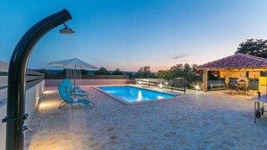 A swimming pool with lounge chairs, a stone patio, a pergola with umbrellas, and a stone oven. - Awesome apartment in Gornje Rastane (Gornje Rastane)