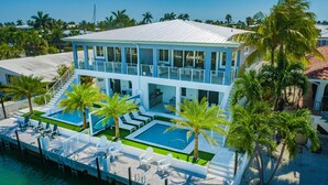 A two-story building with a pool area, including a smaller pool and lounge chairs. - Canal Front with Cabana Club Privileges! Paddleboards, Bikes, Kayak in KCB! (Key Colony Beach)