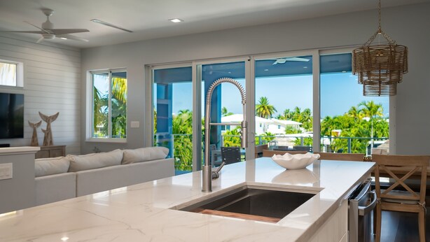 A modern kitchen with a large island, a built-in oven, and a view of the outdoors. - Canal Front with Cabana Club Privileges! Paddleboards, Bikes, Kayak in KCB! (Key Colony Beach)