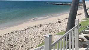 A beach with clear blue water, a sandy shore, and a white fence. - Canal Front with Cabana Club Privileges! Paddleboards, Bikes, Kayak in KCB! (Key Colony Beach)