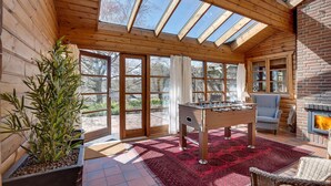 Una habitación acogedora con mesa de fútbol, chimenea y ventanas amplias.