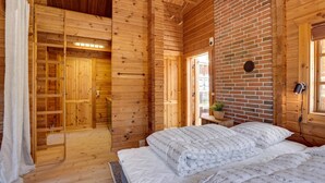 Una habitación de cabaña de madera con una cama, un armario de madera y una pared de ladrillo.