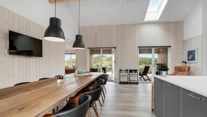 Eine moderne Küche mit Holztischplatte, schwarzen Stühlen und einem großen Esstisch aus Holz.