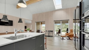 Eine moderne Küche mit einer großen Kücheninsel, integrierten Geräten und einer Glastür zum Patio mit Sitzgelegenheiten.