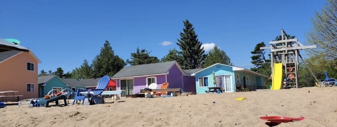 A beachside property with colorful houses, a sandy beach, and a playground.