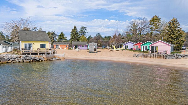 A waterfront property with colorful beach houses, a sandy beach, and a clear view of the water. - Aloha Beach Club Resort (Oscoda)