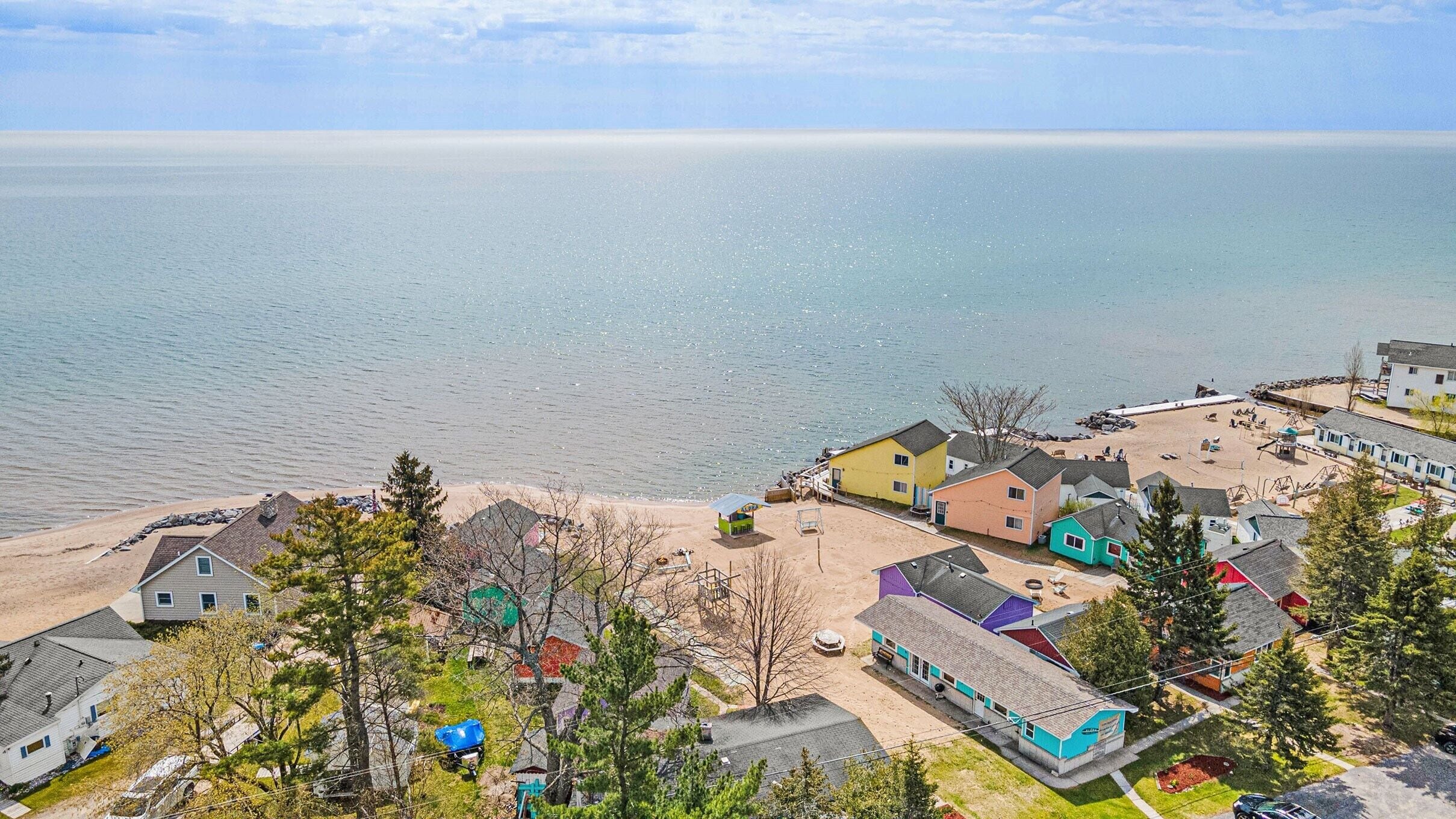 A coastal residential area with colorful houses, a sandy beach, and a view of the sea.