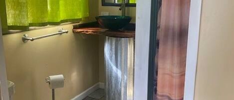 A bathroom with a toilet, a sink with a mirror above it, and a shower curtain.