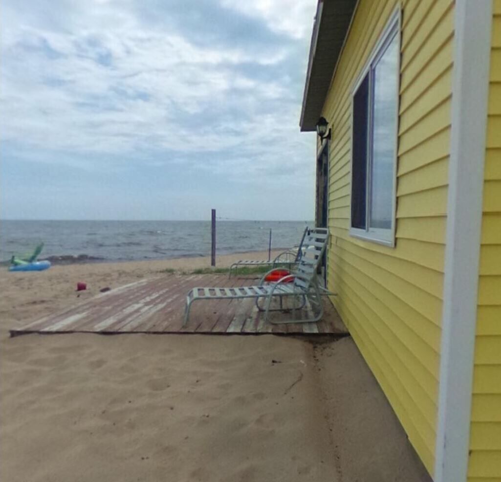 A beach house with a wooden deck and metal chairs.
