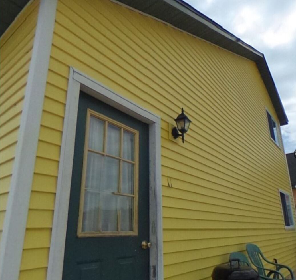 A yellow building with a green door and a window.