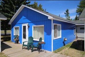 A blue cabin with a porch, two green Adirondack chairs, and a small table. - Aloha Beach Club Resort (Oscoda)