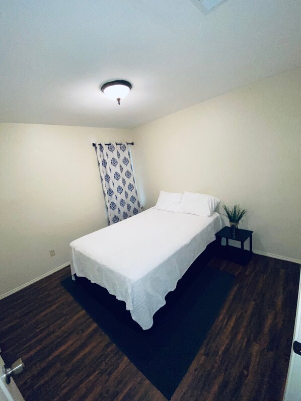 Une chambre à coucher avec un lit, une table de chevet, une plante en pot et un luminaire au plafond.