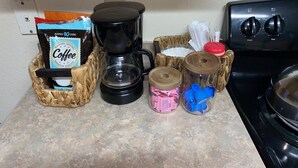 Uma bancada de cozinha com uma cafeteira, um saco de café e dois recipientes com tampas.