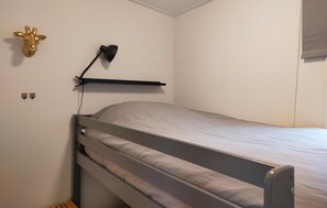 A single bed with a headboard, a wall-mounted lamp, and a decorative giraffe head.