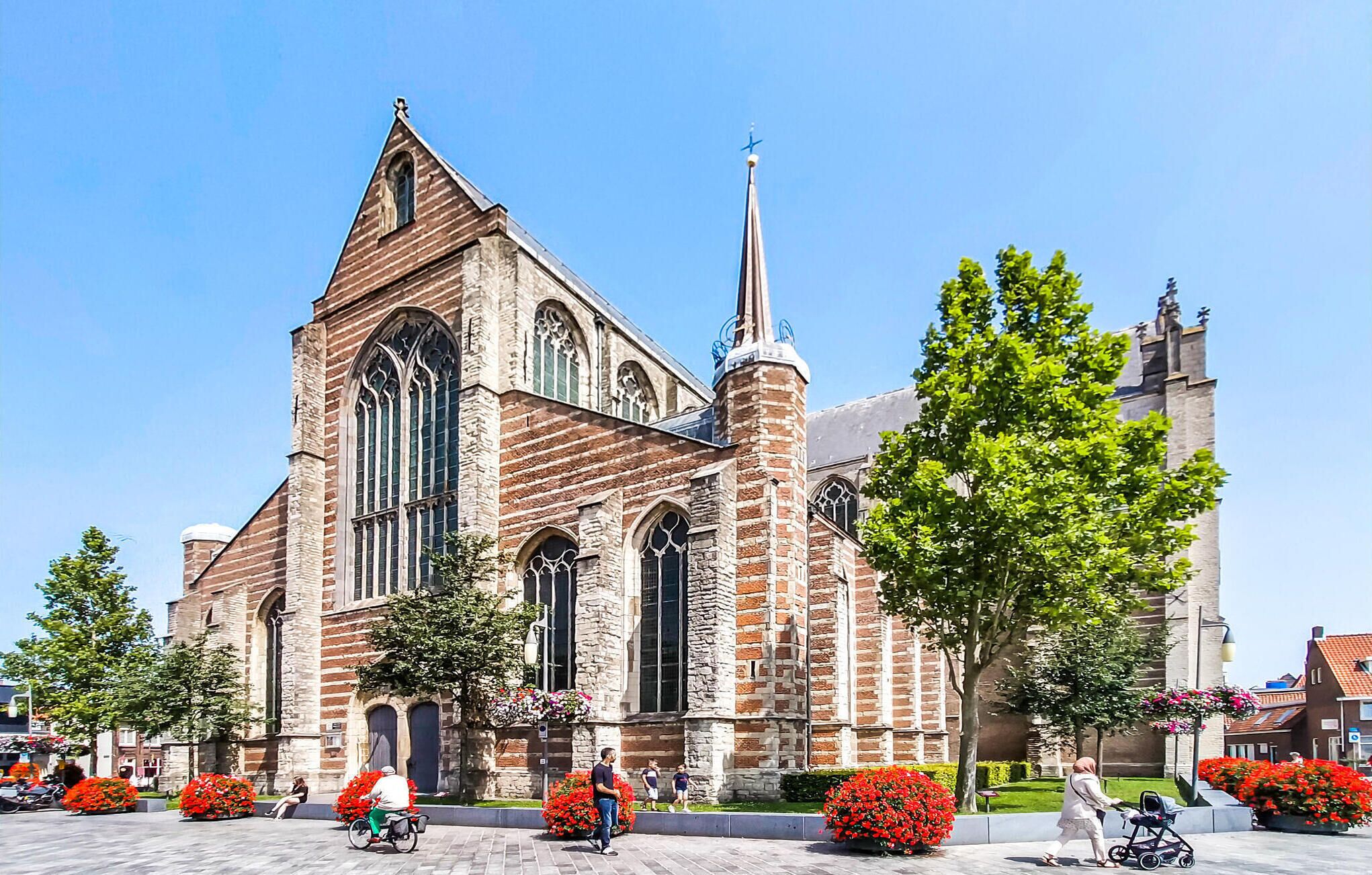 Une église historique dotée de grandes fenêtres en arc et d’une haute flèche.