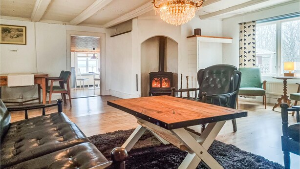 Un salon chaleureux avec une cheminée, un lustre et une vue sur l’extérieur.