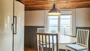 Une cuisine avec une table ronde, deux chaises, un luminaire suspendu et une vue par la fenêtre.