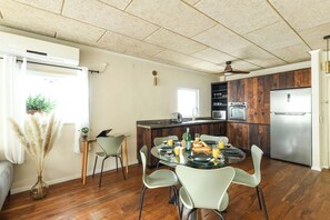 A modern kitchen with a dining area, wooden cabinets, and a stainless steel refrigerator.