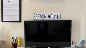 A television on a white cabinet with a sign above it that reads "BEACH HOUSE." - Hop, skip, jump to the beach! (Point Pleasant Beach)