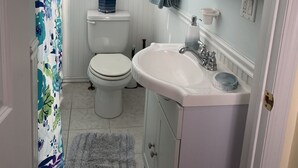 A bathroom with a toilet, sink, and a shower curtain. - Hop, skip, jump to the beach! (Point Pleasant Beach)