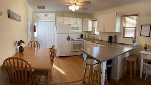 A kitchen with white cabinets, a central island, wooden chairs, and a dining table. - Hop, skip, jump to the beach! (Point Pleasant Beach)