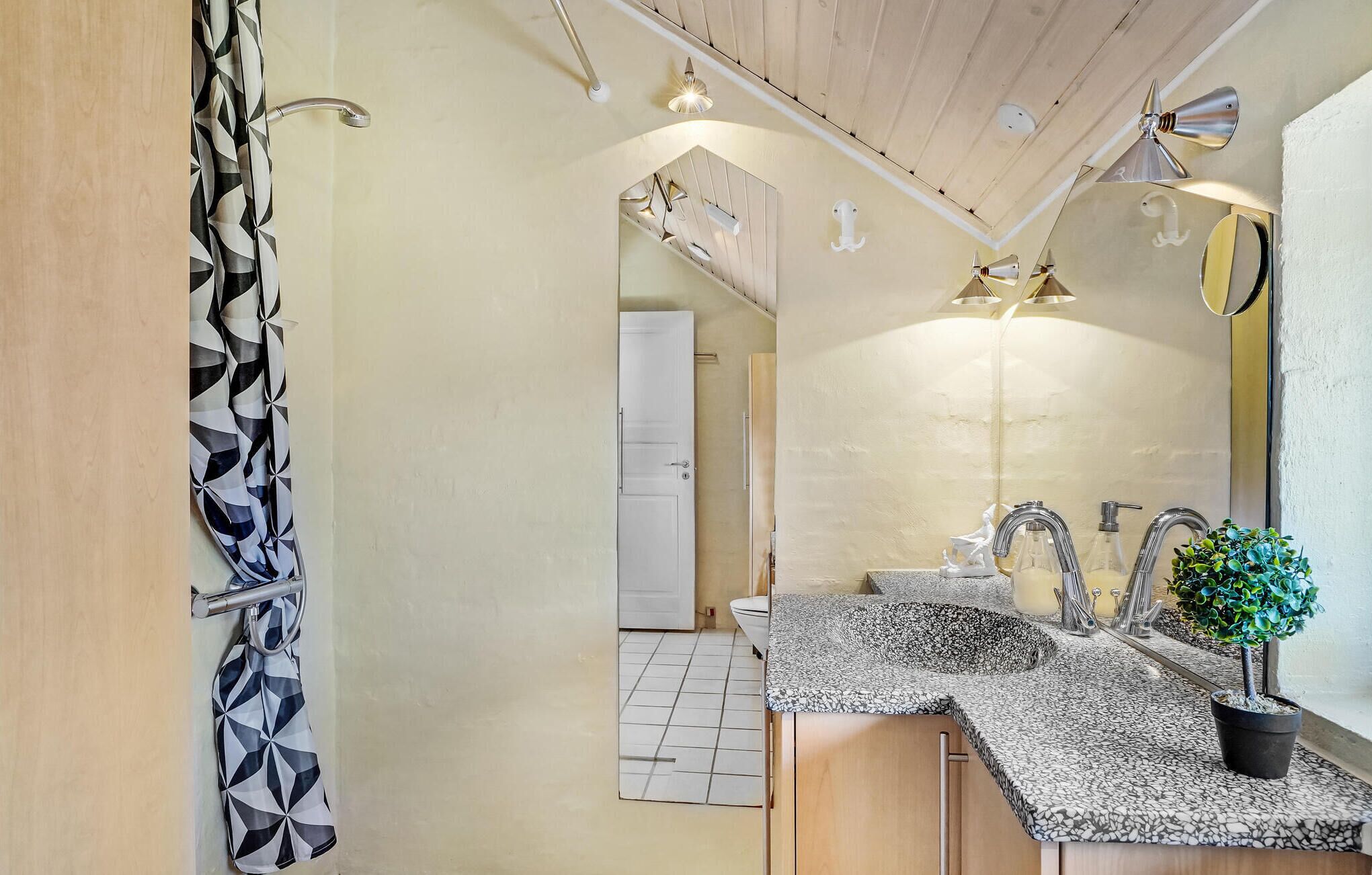 Un baño moderno con un espejo grande, dos lavamanos y una planta en maceta.