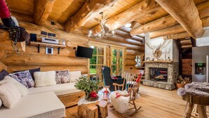 A cozy log cabin interior with a stone fireplace, wooden furniture, and a television mounted on the wall. - Amazing home in Hlevci with sauna (Hlevci)