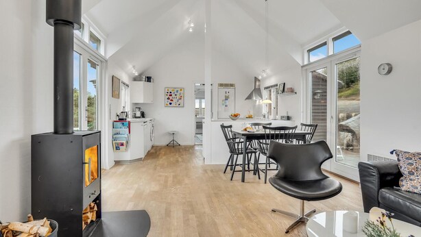 A spacious kitchen with modern appliances, a dining area with black chairs, and a large window providing natural light.