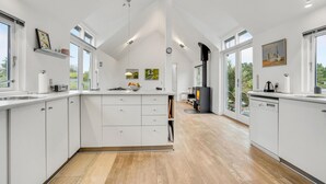 A modern kitchen with white cabinetry, a central island, and large windows providing natural light.