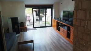 Un salón espacioso con televisor grande, armarios de madera y tragaluz.