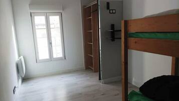 Ein Zimmer mit einem Etagenbett, einem Kleiderschrank und einem Fenster.