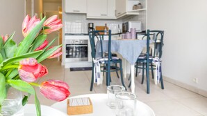 Una cocina moderna con armarios blancos, una mesa de comedor con sillas y un jarrón de tulipanes rosados sobre la mesa.