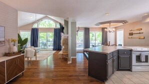 A spacious kitchen with a central island, a dining area with a view, and a living room with a large window. - Spacious Family Lake House In Quiet Cove | 45 (Sunrise Beach)
