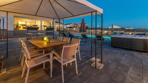 Eine Terrasse im Freien mit Esstisch, Stühlen und einem Whirlpool.