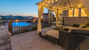Ein überdachter Außenbereich mit Pool, ausgestattet mit Korbmöbeln und einer Lichterkette als Dach.