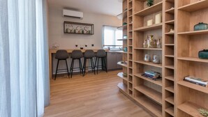 Eine moderne Küche mit Holzhockern, einer eingebauten Bücherwand und einem Fenster mit Tageslicht.