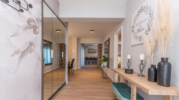 Ein modernes Interieur mit Holzboden, einer Bank, einem Empfangstresen und einer Wand mit einem Willkommensschild.
