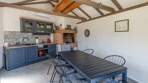 A kitchen with a wooden table and chairs, a brick oven, and a dartboard.