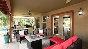 An outdoor patio with seating, a grill, and a ceiling fan.