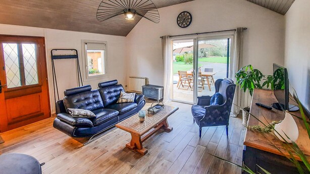 A living room with a leather sofa, a wooden coffee table, a blue armchair, and a television. - 2 bedroom lovely home in Bréhan (Bréhan)