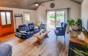 Ein Wohnzimmer mit einer Ledersofa, einem Holztisch, einem blauen Sessel und einem Fernseher.