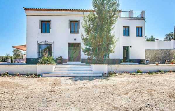A two-story building with a white facade, multiple windows, and a central entrance with steps.