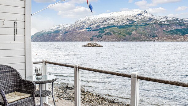 A view from a balcony overlooking a lake with a snow-capped mountain in the background.