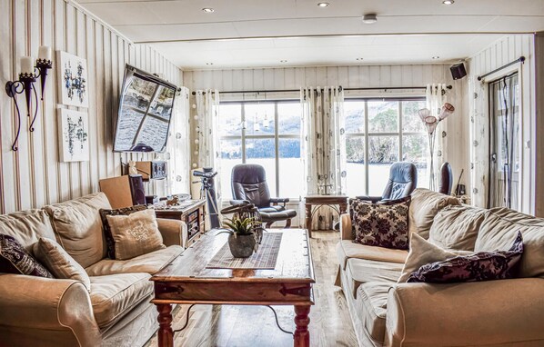 A cozy living room with two leather sofas, a wooden coffee table, and a large window offering a scenic view.