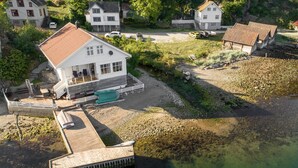 A white house with a red roof, a dock, and a small boat.